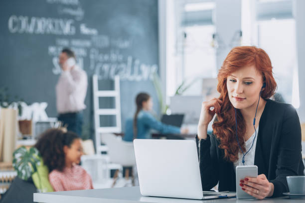 Relaxed, young worker of creative agency using laptop, listening music